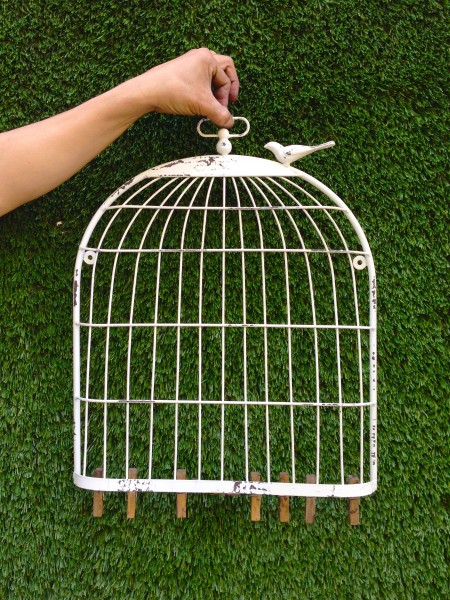 white birdcage wall hanging with wooden clips